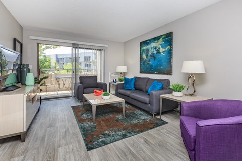 A living room with a purple chair and a grey couch.