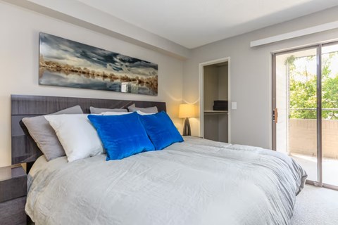 A bedroom with a large bed and a painting on the wall.