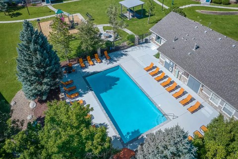 An aerial view of a swimming pool surrounded by orange lounge chairs and trees.