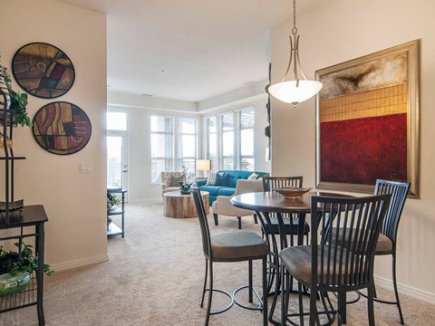 A dining room with a table set for two and a large painting on the wall.
