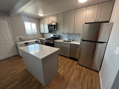 A kitchen with a white island and stainless steel appliances.