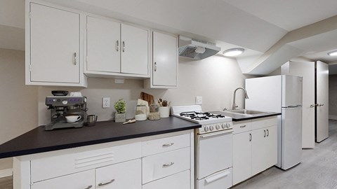 A kitchen with white cabinets and black countertops.