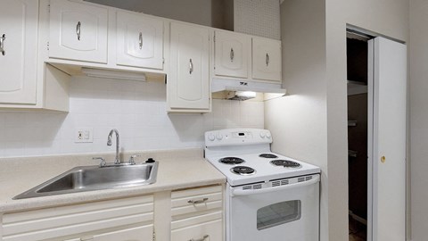 A white kitchen with a stove and sink.
