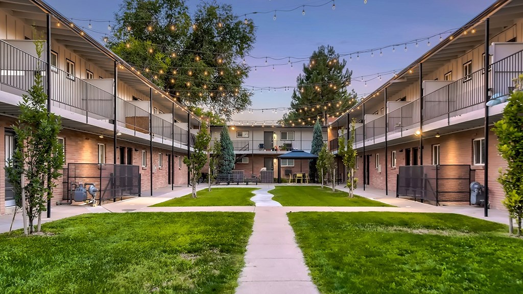A courtyard surrounded by apartment buildings with a walkway in the middle.