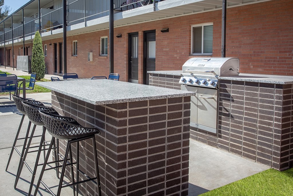 A brick patio with a bar and stools.