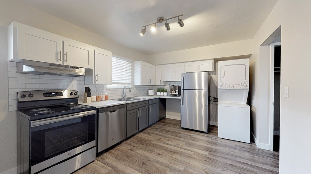 A modern kitchen with stainless steel appliances and wooden floors.