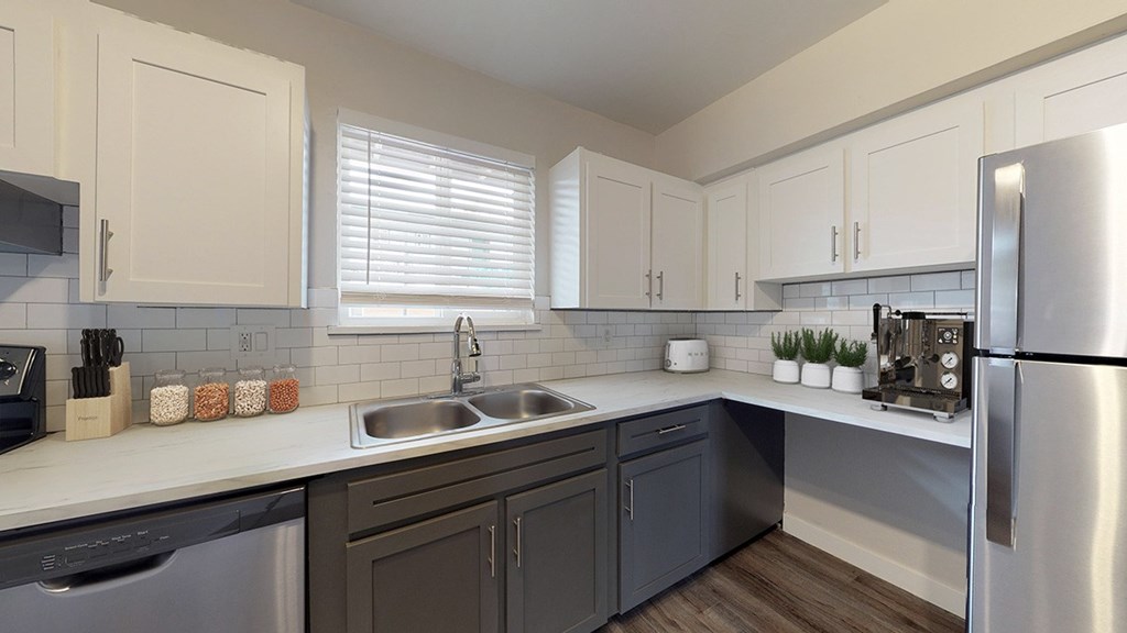 A modern kitchen with a stainless steel refrigerator, sink, and cabinets.