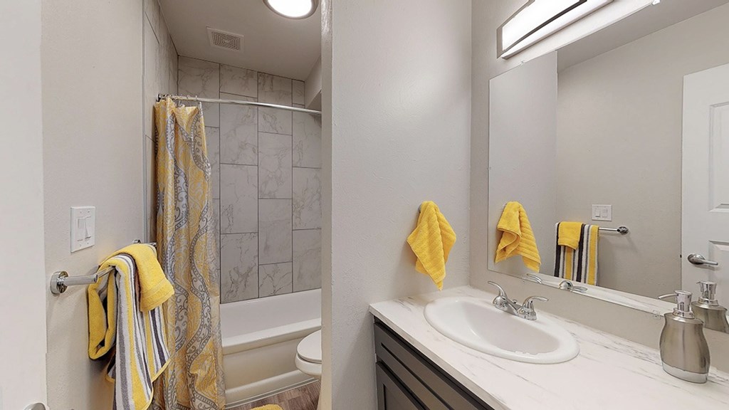 A bathroom with a white sink, a striped towel, and a yellow towel.