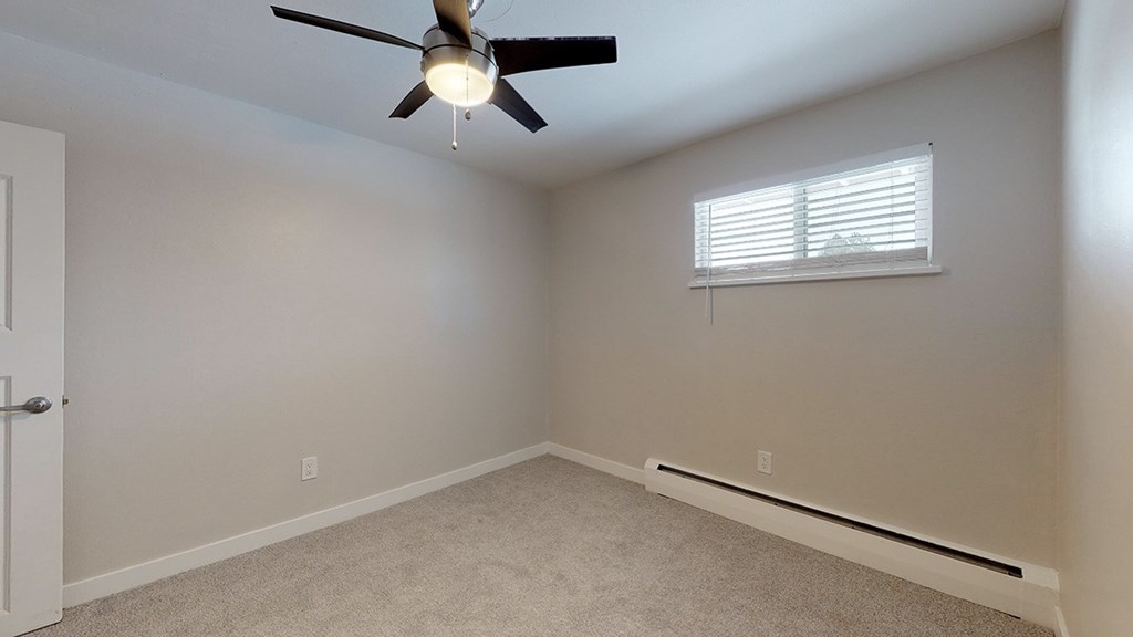 A room with a ceiling fan and a window with blinds.