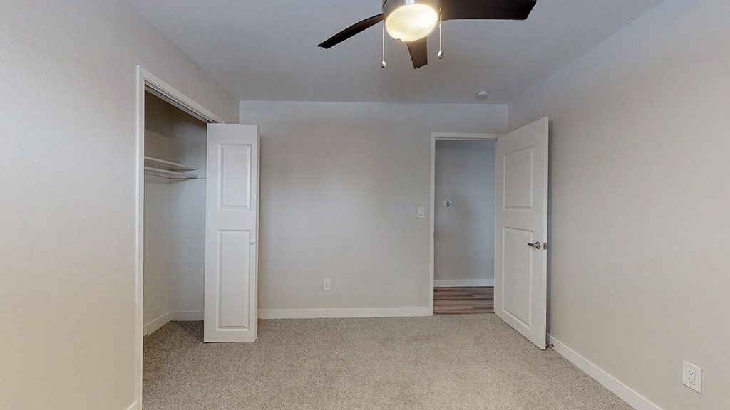 A room with a ceiling fan and two doors.