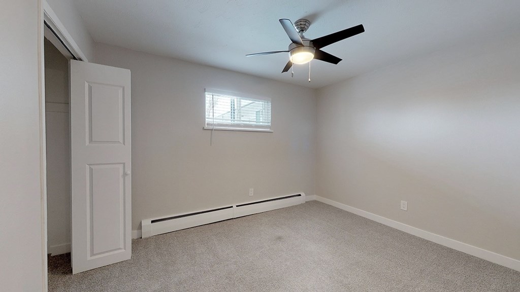 A room with a ceiling fan and a window.