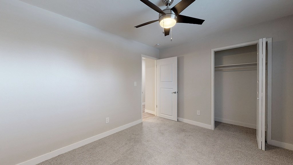 A room with a ceiling fan and a door.