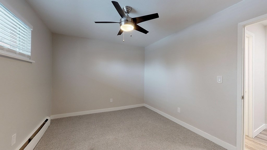 A room with a ceiling fan and carpeted floor.