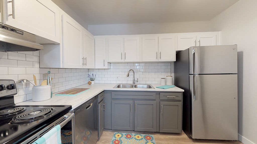 A kitchen with a stove, sink, and refrigerator.