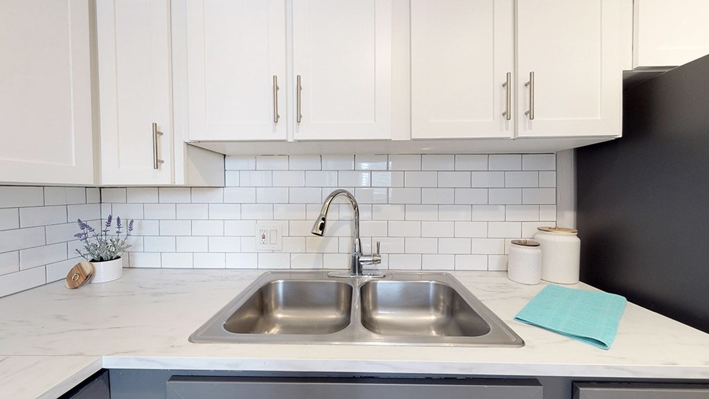A kitchen with a white countertop and a black refrigerator.