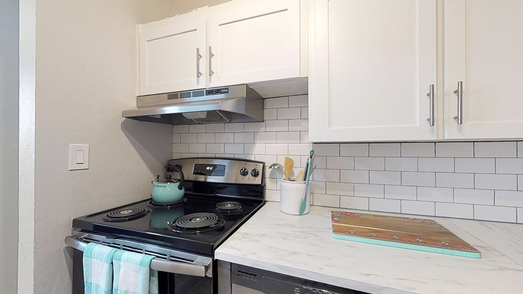 A kitchen with a stove and a white counter.