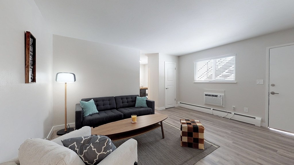 A living room with a black couch and a grey ottoman.