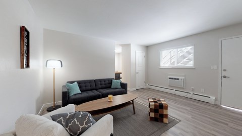 A living room with a black couch and a grey ottoman.