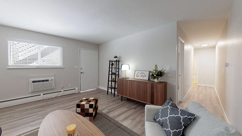 A living room with a couch, a coffee table, and a window with blinds.