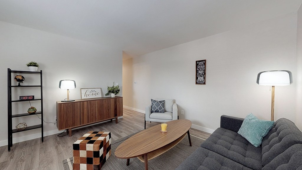 A living room with a black couch, a wooden coffee table, and a wooden bookshelf.