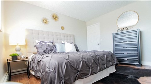 A bedroom with a large bed and a lamp on a side table.