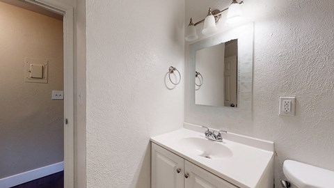 A bathroom with a sink, mirror, and toilet.