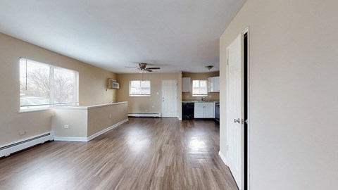 A spacious room with wood flooring and a ceiling fan.