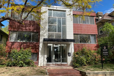 A building with a red and white facade has a black sign in front of it.