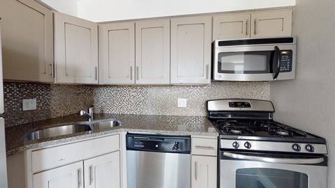 A kitchen with a stove, oven, dishwasher, and microwave.