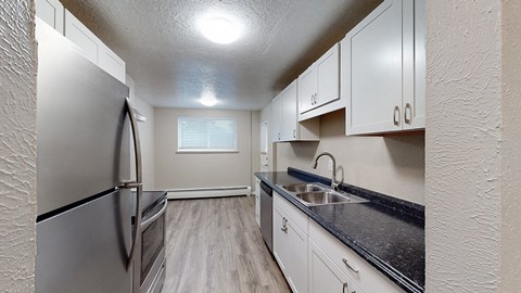 A kitchen with a stainless steel refrigerator and a black countertop.