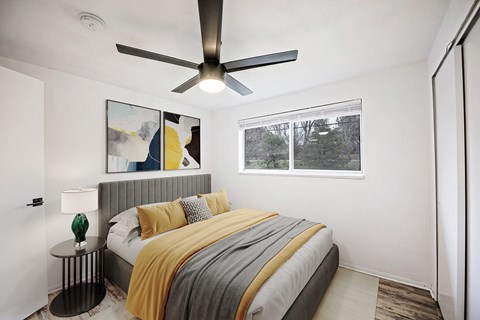 A bedroom with a bed, a ceiling fan, and a window.