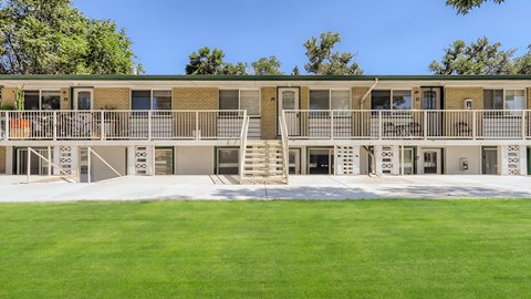 A 2 story building with white railing and steps leading to each level. Grassy area in front.