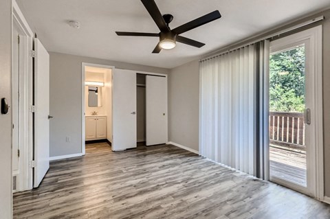 A spacious room with a ceiling fan and sliding glass doors leading to a deck.