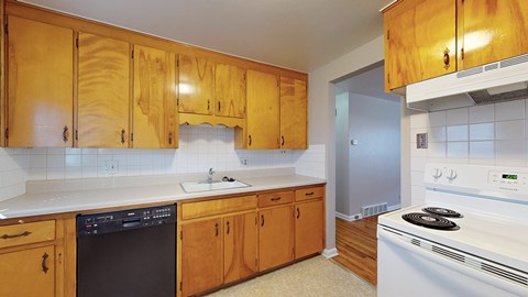 A kitchen with wooden cabinets and a white stove.