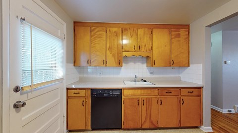 A kitchen with wooden cabinets and a black dishwasher.
