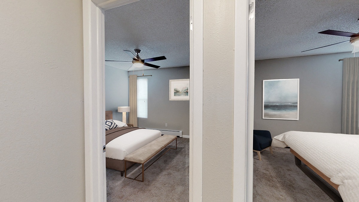 A bedroom with a bed, chair, and a ceiling fan.