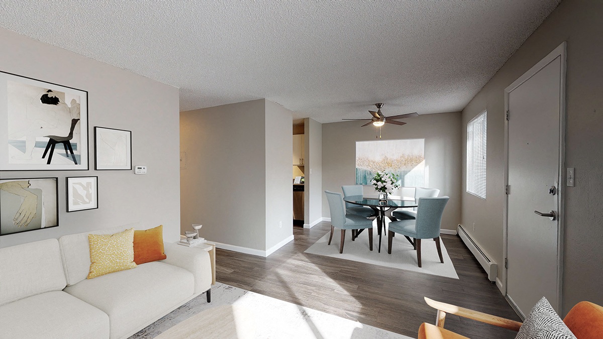 A living room with a white couch and a dining table with chairs.