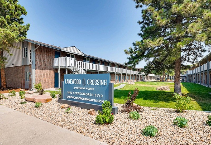 A sign for Lakewood Crossing Apartment Homes stands in front of a building.