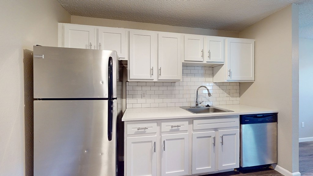 A kitchen with white cabinets and a stainless steel refrigerator.