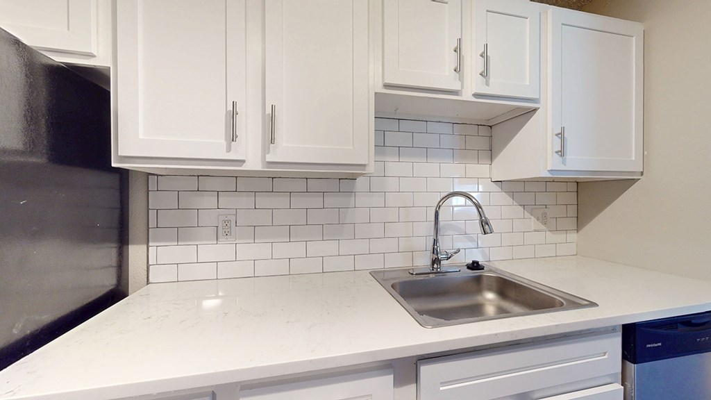 A kitchen with white cabinets and a black refrigerator.