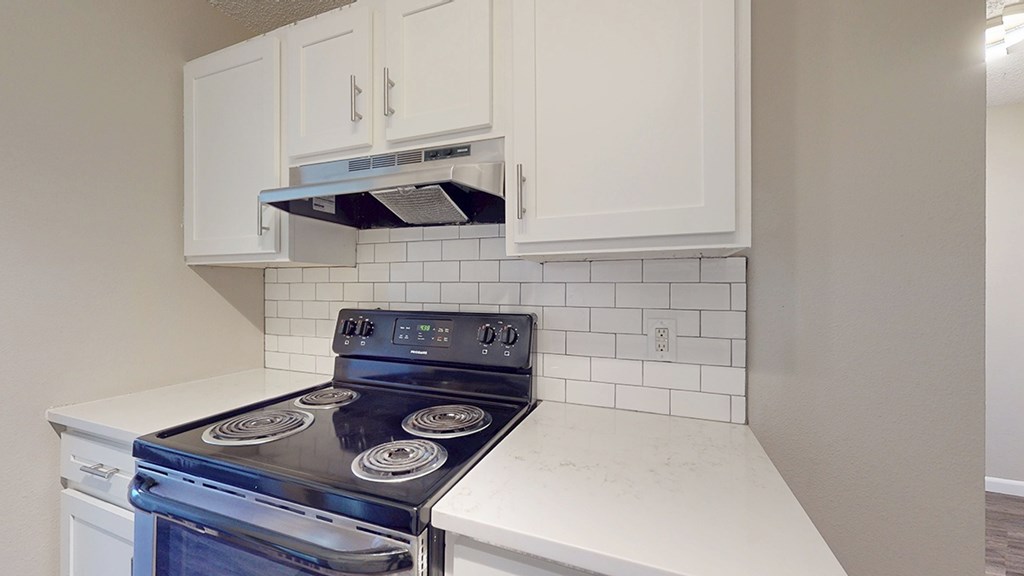 A white kitchen with a black stove top oven.