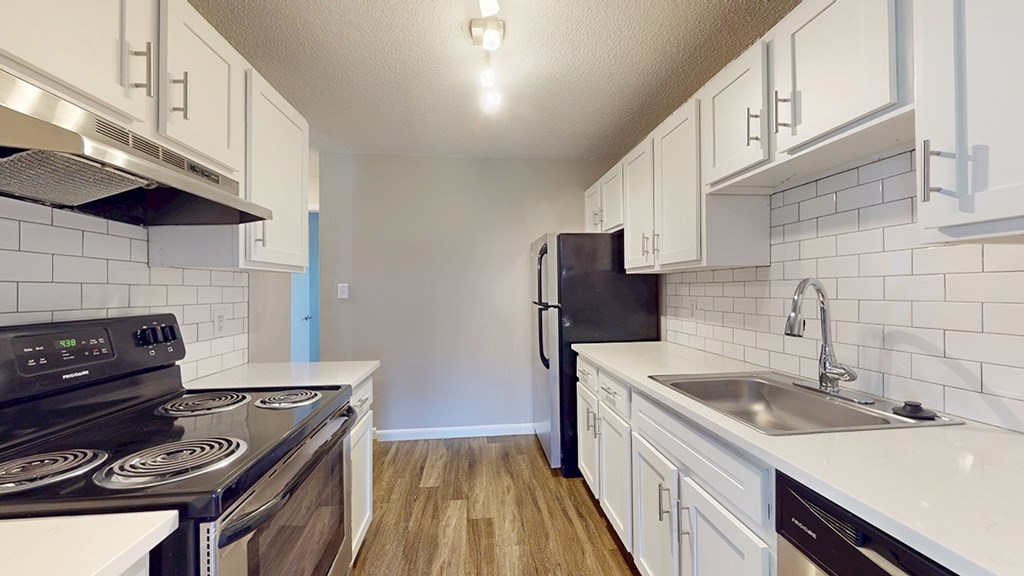 A kitchen with white cabinets and a black stove top oven.