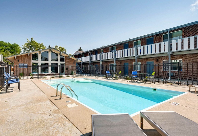 A swimming pool surrounded by a fence and chairs.