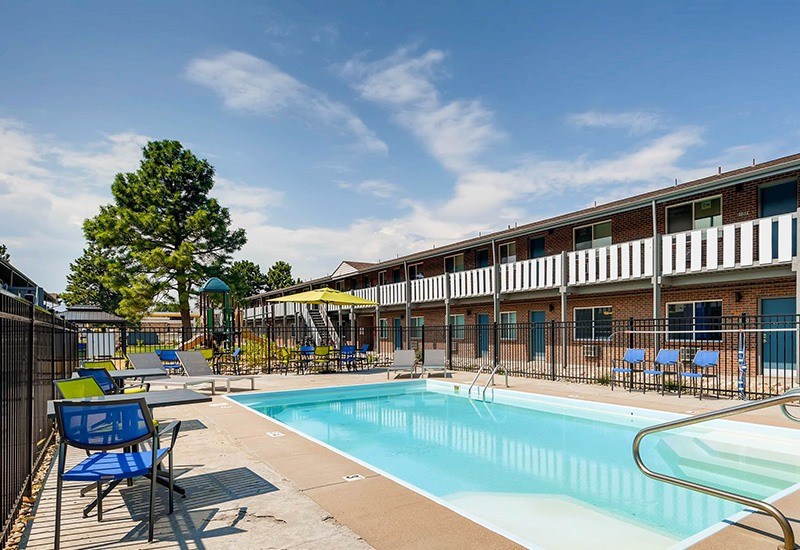 A pool area with chairs and a building in the background.