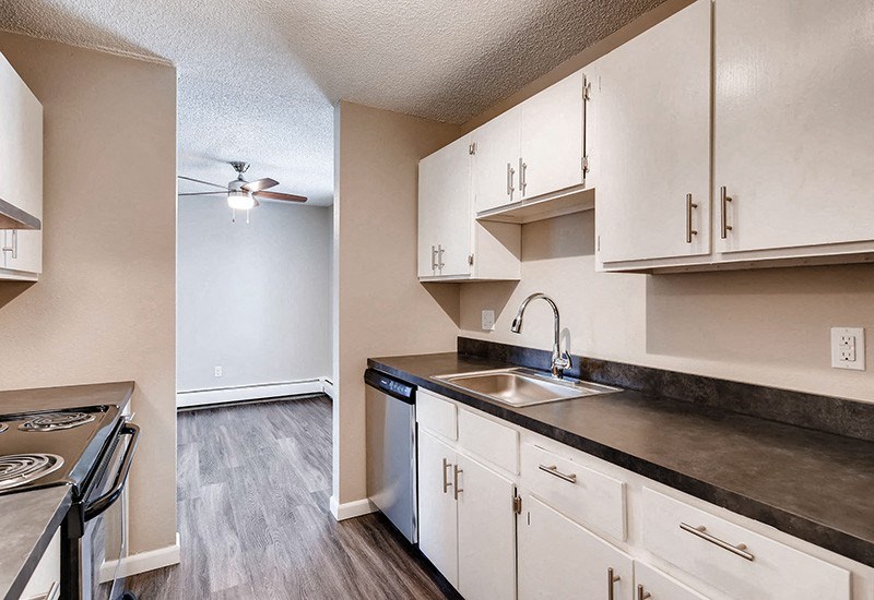 A kitchen with white cabinets and a black countertop.