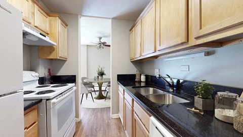A kitchen with wooden cabinets and black countertops.