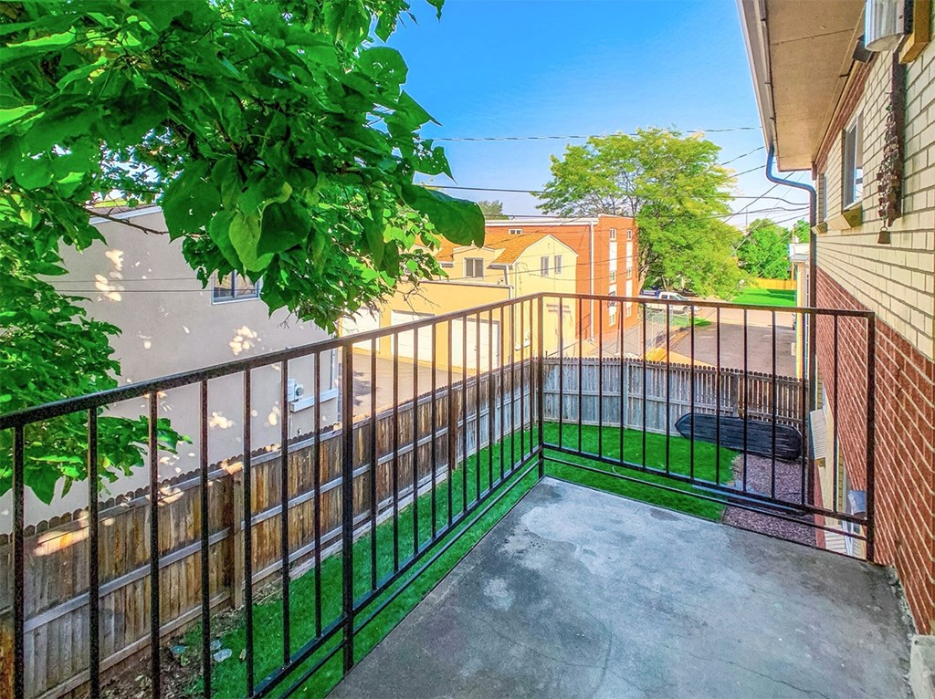A balcony with a black railing and a green lawn.