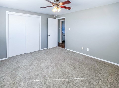 A room with a ceiling fan and two doors.