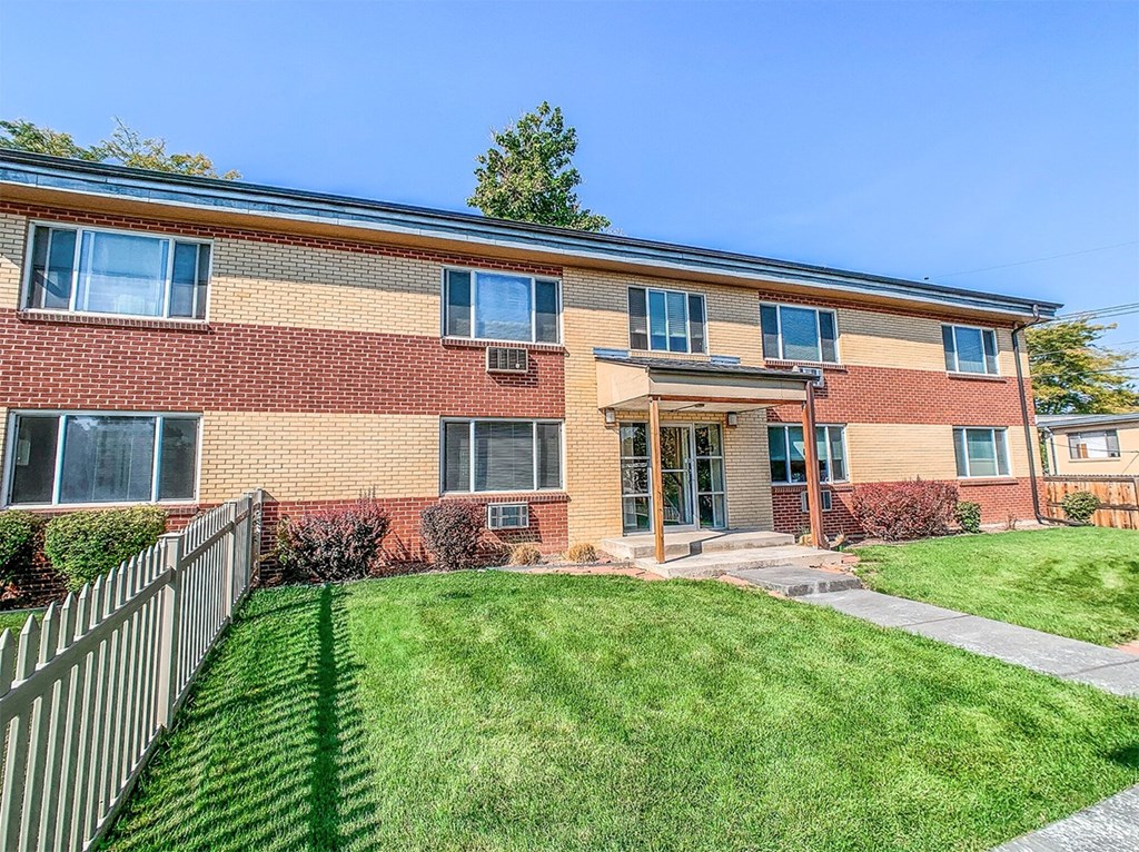 A red brick building with a green lawn in front.