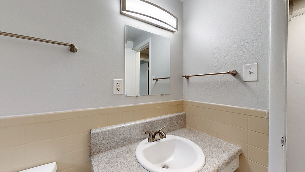 A bathroom with a sink, mirror, and towel rack.